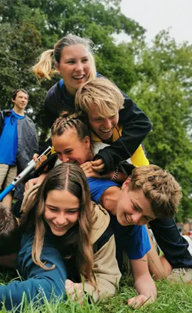 Leden liggen lachend op elkaar in het gras